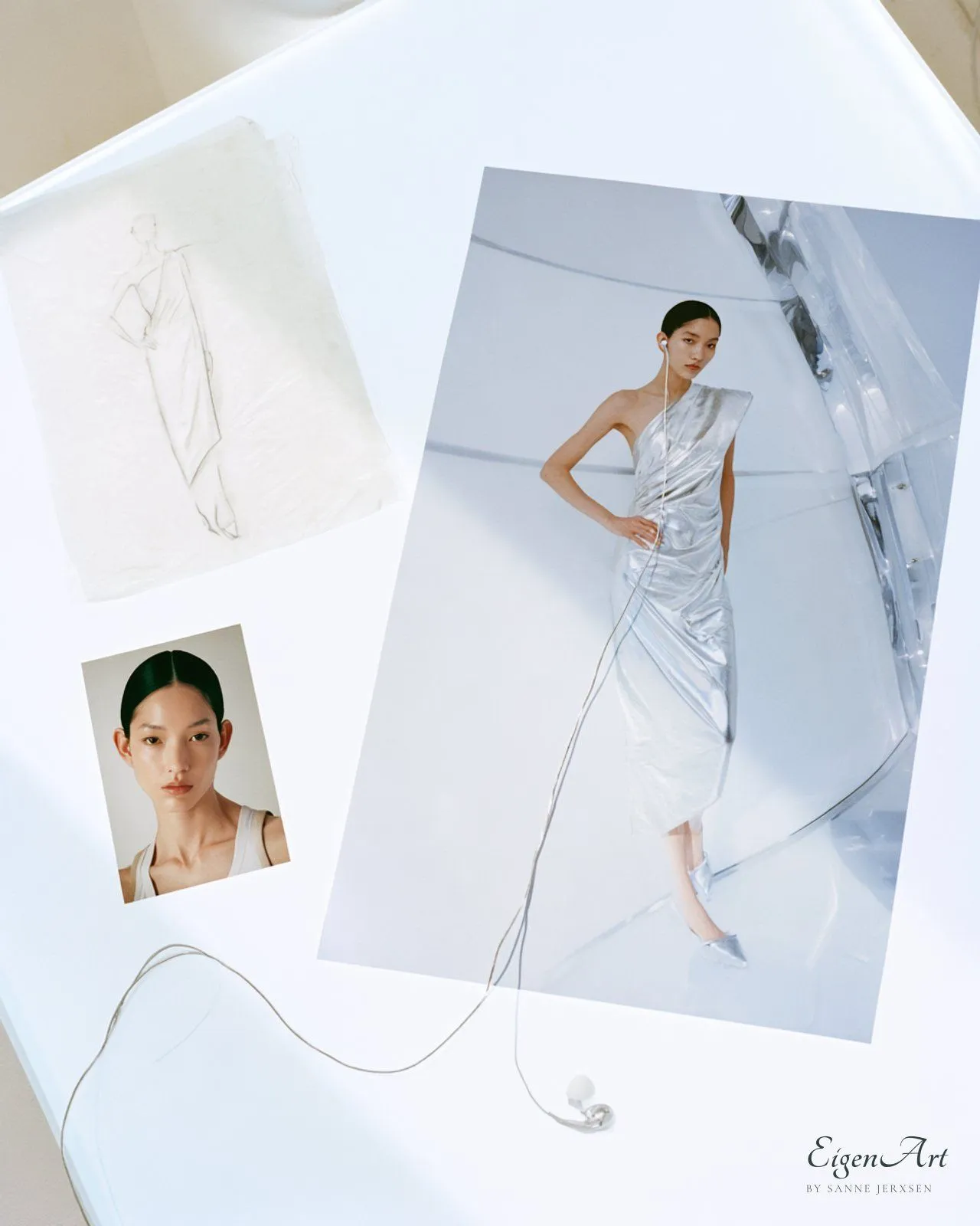 Moodboard auf hellem Leuchttisch mit Bleistiftskizze, Polaroid eines Models mit Mittelscheitel und Kampagnenabzug einer Frau im einschultrigen silbernen Kleid, deren weißes Kopfhörerkabel aus dem Foto heraus über den Tisch läuft